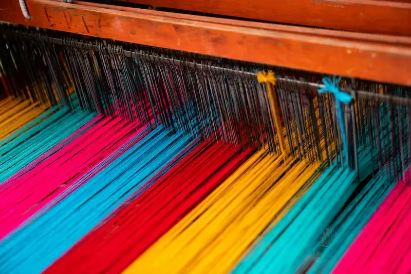 Brightly colored yarns make up a warp on a loom.